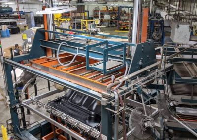 Factory floor with large industrial machinery, metal structures, and equipment, used for manufacturing or assembly work, including advanced seating systems.